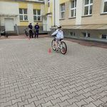 Uczennica jedzie na rowerze w tle policjanci.jpg