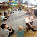 grupa uczniów słucha czytanej książki przez nauczyciela (8).jpg