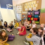 grupa uczniów słucha czytanej książki przez nauczyciela (1).jpg