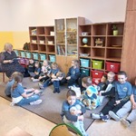 Grupa uczniów słuchających i nauczyciel czytający książkę.jpg (1).jpg