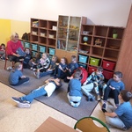 Grupa uczniów słuchających i nauczyciel czytający książkę.jpg