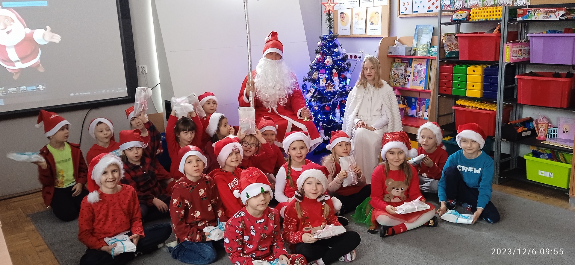 Dzieci ze Św. Mikołajem siedzą wokół klasowej choinki.jpg
